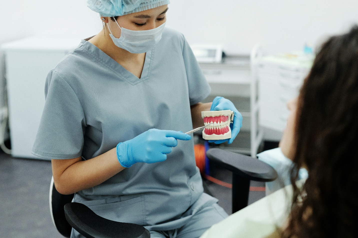 a woman in scrubs holding a teeth model