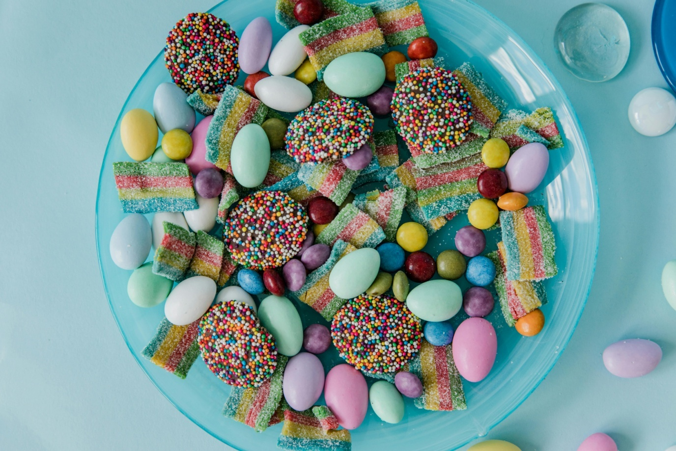 A blue colored bowl filled with different kinds of sweets and jellies