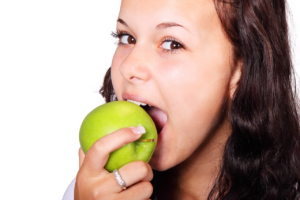 woman biting a green apple