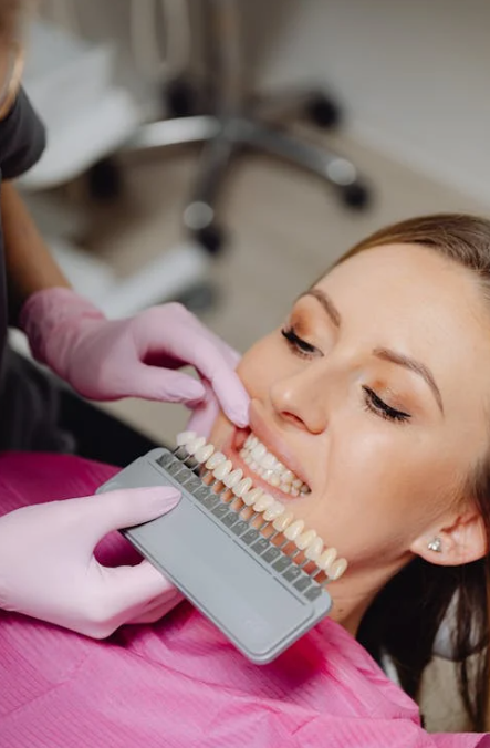 a dentist holding a dental shade guide in front of a patient